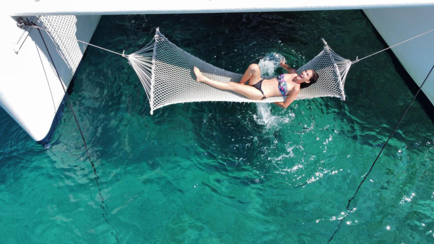 Une fille se détend dans un hamac à l'arrière d'un catamaran