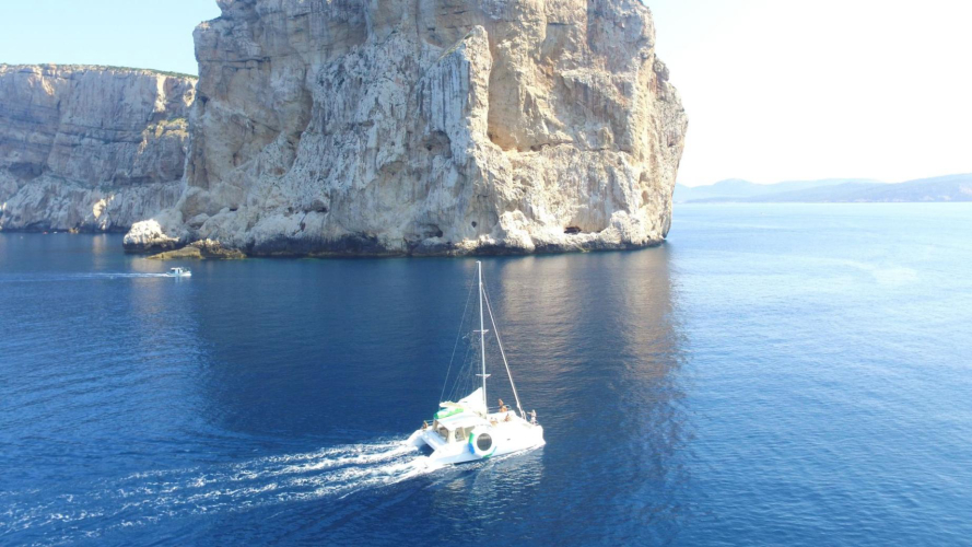 Catamarano naviga al lago del faraglione di Capo Caccia ad Alghero