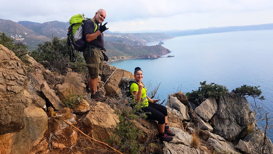 Two people during a dry canyoning excursion with a view of the south-west coast of Sardinia