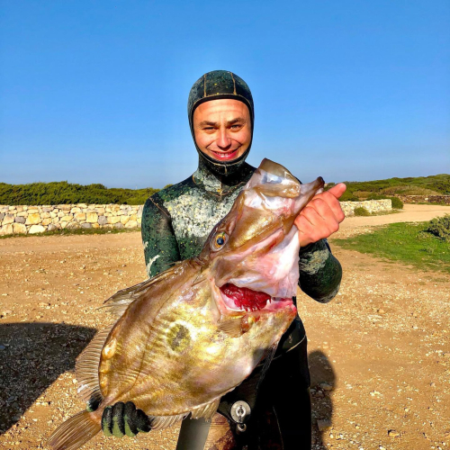 Wanderer mit frisch gefangenem Fisch bei einem Ausflug nach Porto Conte