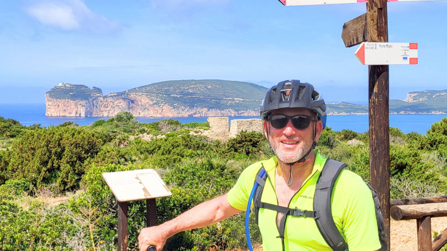 Niño con casco y ebike explora Alghero con Capo Caccia a sus espaldas