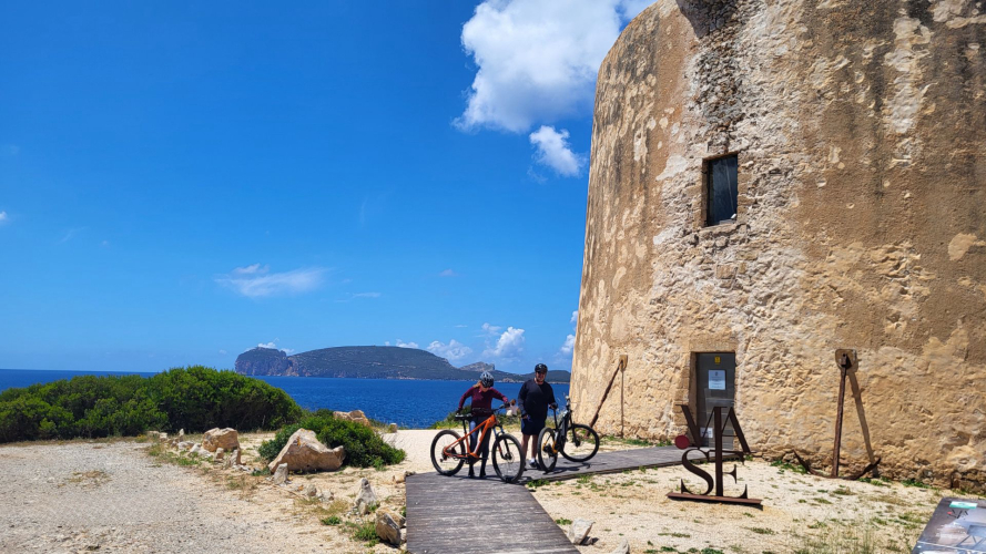 Torre con el Capo Caccia detrás durante la visita guiada en ebike para descubrir la zona de Alghero