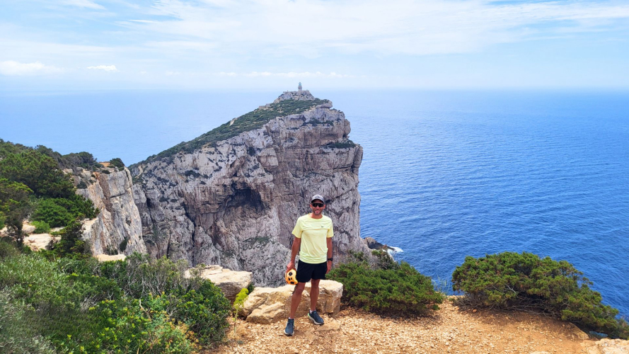 Senderista durante experiencia ebike con acantilados detrás y mar azul de Alghero