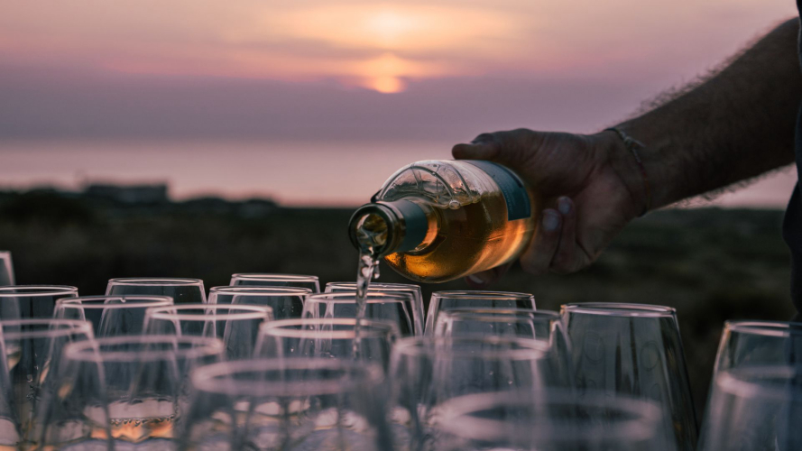 Einschenken von Wein aus Gläsern und Sonnenuntergang