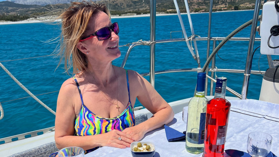 Signora fa l'aperitivo a bordo della barca a vela nella Spiaggia delle Vacche