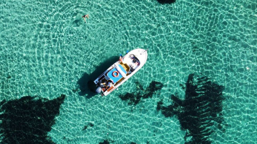 Vista aérea del barco navegando por las aguas cristalinas de Stintino