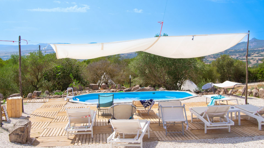 Piscine avec chaises longues, tables et chaises à l'ombre en pleine nature