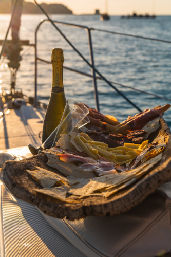 Aperitif mit Weißwein bei Sonnenuntergang in Stintino auf einem Segelboot
