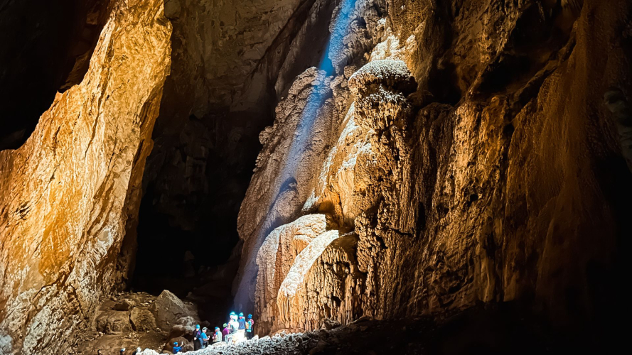 Wanderer hören dem Führer unter dem Lichtstrahl in der Höhle Sa Nurre de Su Hoda in Oliena zu