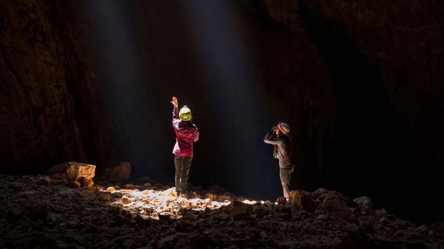 Zwei Wanderer beobachten den Lichtstrahl im Inneren der Höhle Sa Nurre de Su Hoda in Oliena
