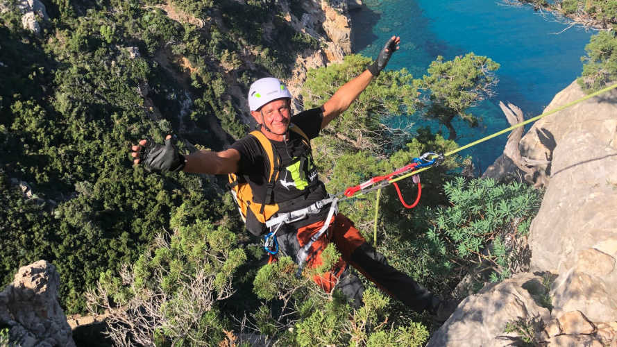 Turista durante abseling con mare turchese del Golfo di Orosei