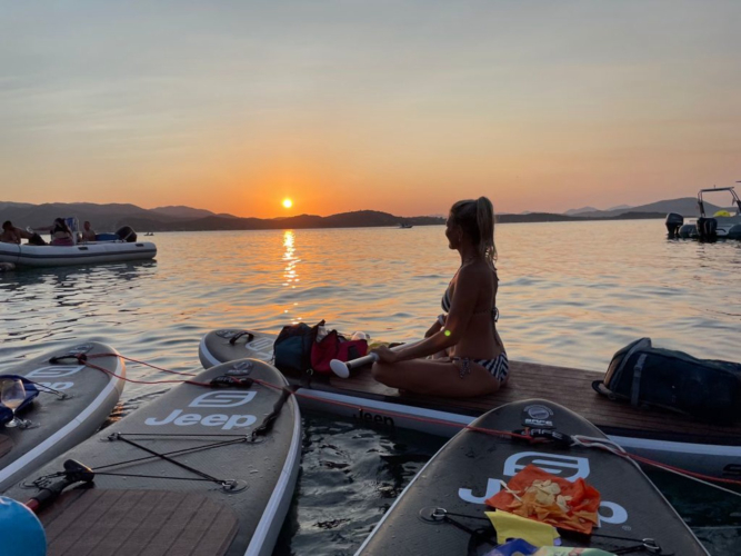 chica en una excursión de SUP al atardecer en el mar de la Costa Esmeralda