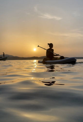 chica en una excursión de SUP al atardecer en el mar de la Costa Esmeralda