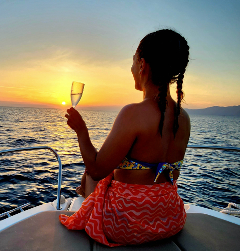 Ragazza mentre brinda ammirando il tramonto nell'isola dei Cavoli