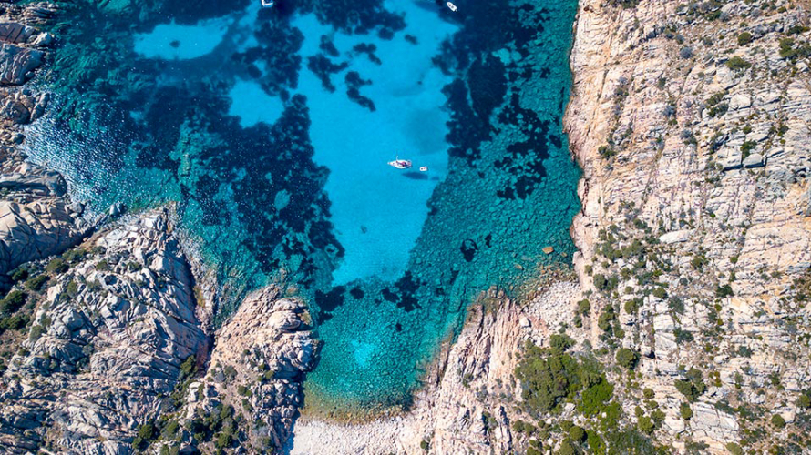 Draufsicht auf ein Boot, das vor einer Insel im Archipel von La Maddalena vor Anker liegt