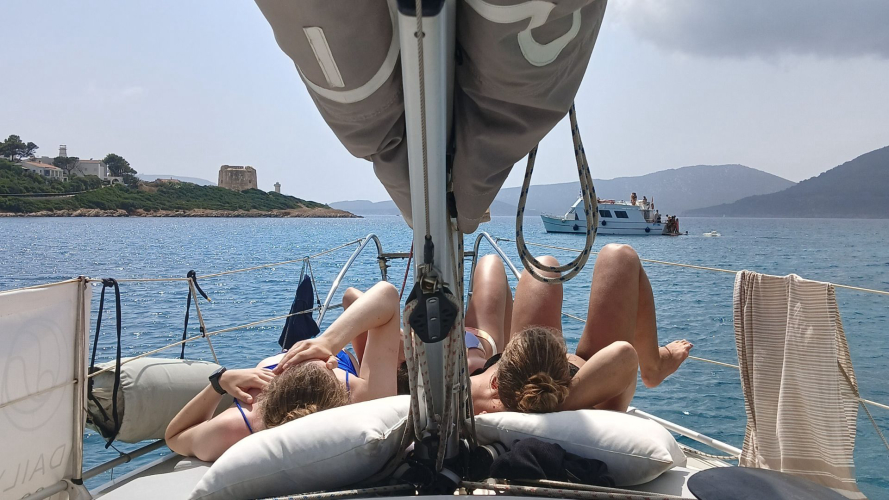 Persone si rilassano a bordo della barca a vela durante il tour a Cala Dragunara