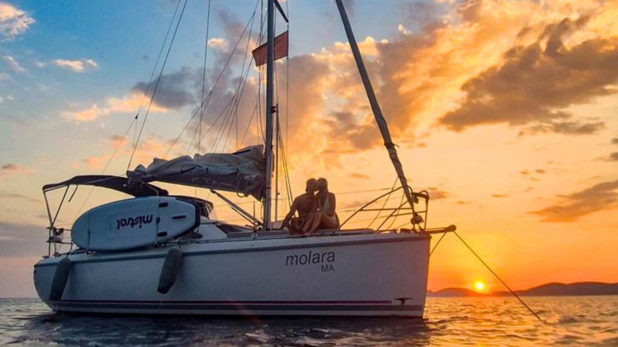 Barca a vela al tramonto durante il tour ad Alghero