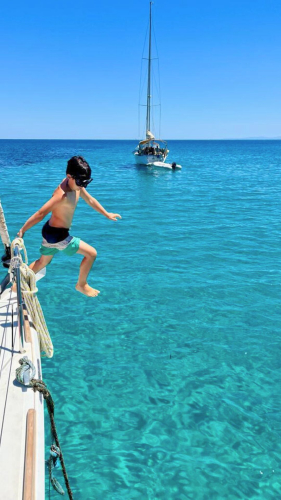 Bambino si tuffa dalla barca a vela durante il tour