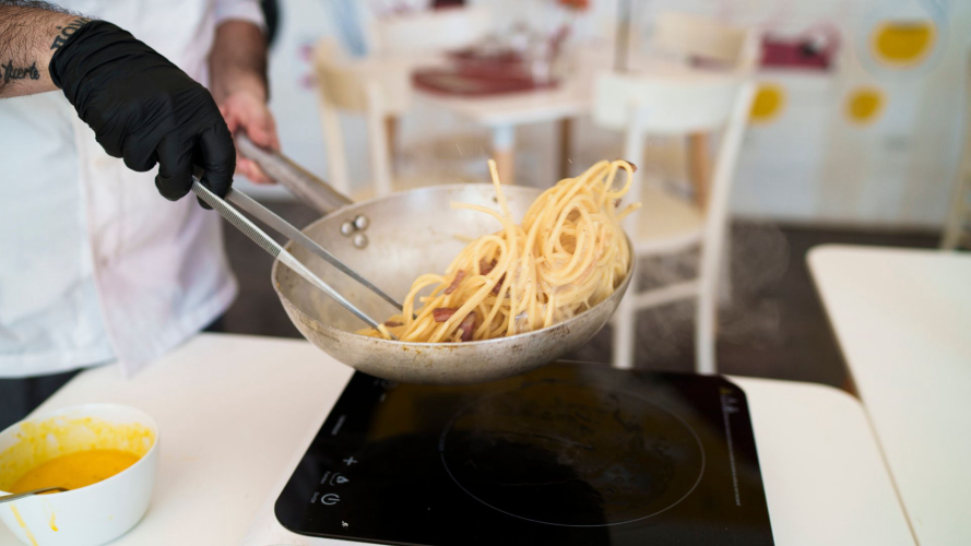 Lo chef prepara la pasta alla carbonara durante la lezione di cucina a Olbia