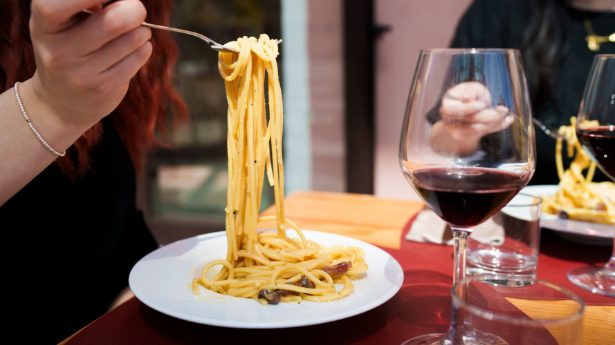 Pasta alla carbonara accompagnata da un calice di vino durante la lezione di cucina a Olbia