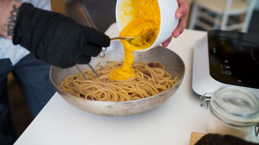 Condimento della pasta durante la lezione sulla pasta alla carbonara
