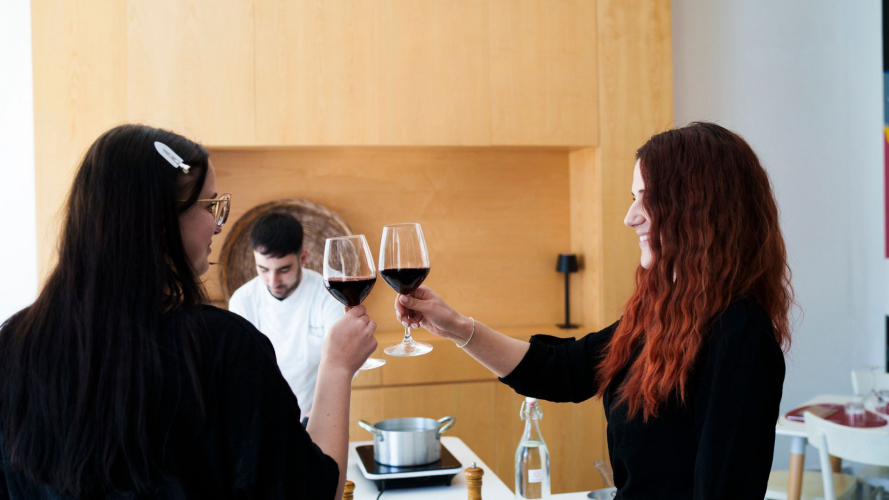 Due ragazze brindano durante la lezione di cucina sulla pasta alla carbonara