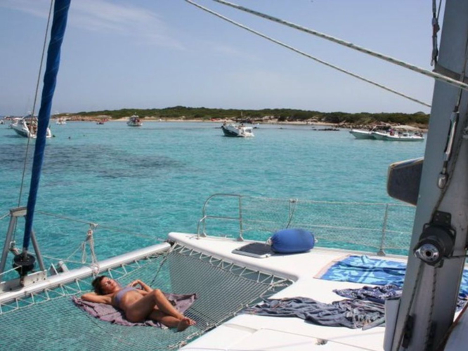 Mädchen beim Sonnenbad auf dem Lagunenkatamaran im klaren Wasser des Meeresschutzgebietes La Maddalena