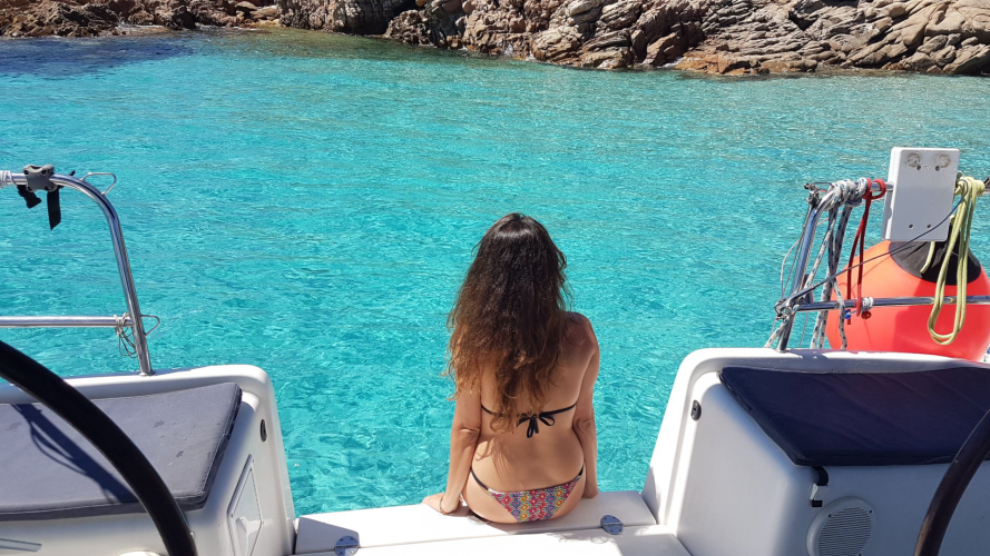 Mädchen, das auf dem Katamaran sitzt, der in den Inseln des La Maddalena-Archipels angedockt ist
