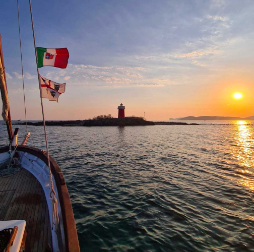 Velero vintage frente a la costa de Alghero al atardecer