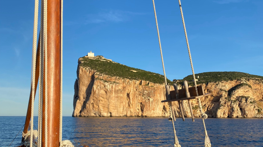 Velero vintage frente a la costa de Alghero al atardecer