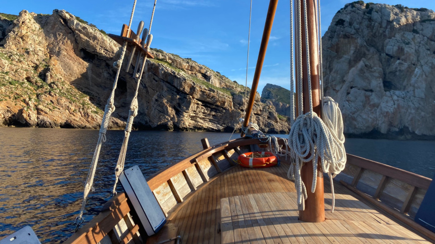 Velero vintage frente a la costa de Alghero al atardecer