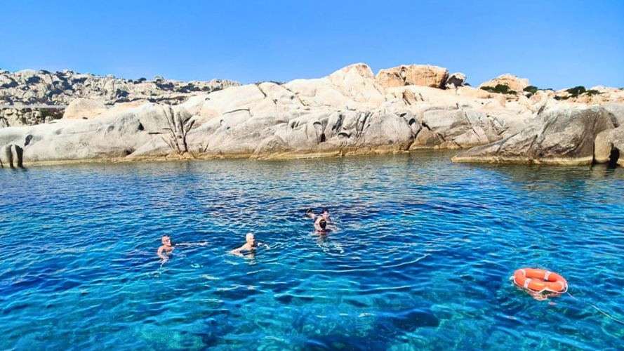 Touristen tauchen vom Motorboot aus während einer Tour durch Asinara
