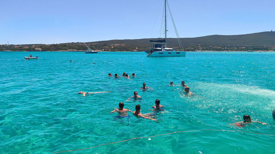 Touristen tauchen vom Motorboot aus während einer Tour durch Asinara