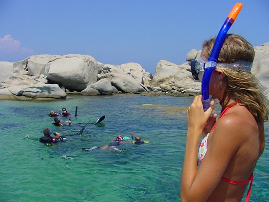 Tourists snorkelling in the crystal-clear waters of Capo Testa
