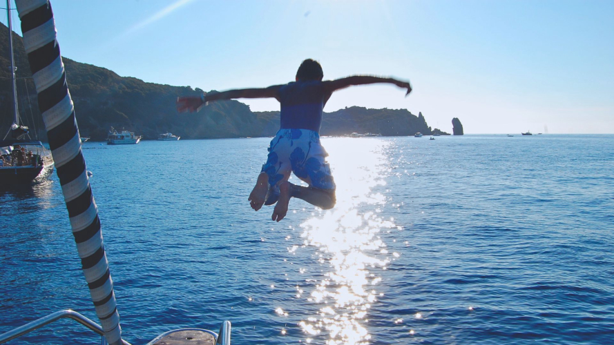 Boy dives off boat during tour in the Gulf of Orosei