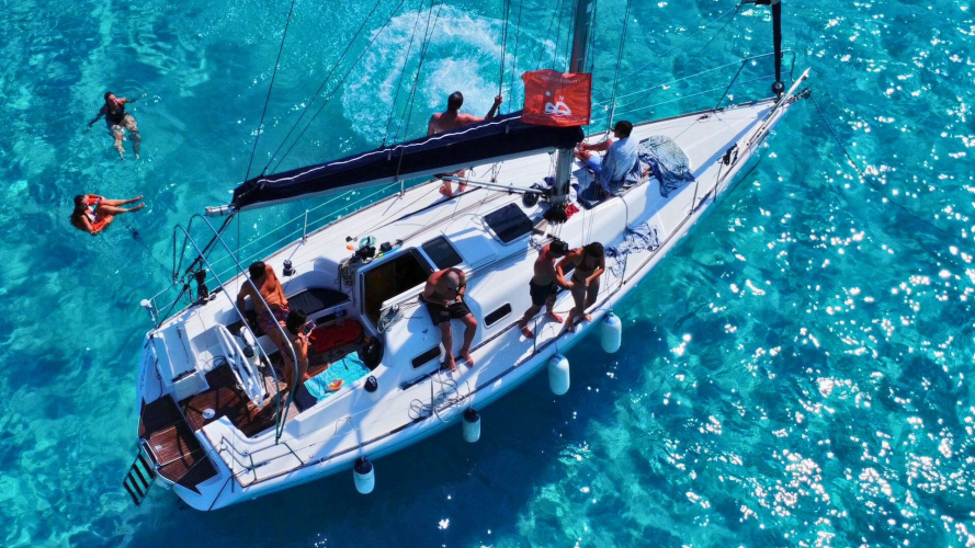 Sailboat seen from above as it sails through the crystal clear waters of Stintino