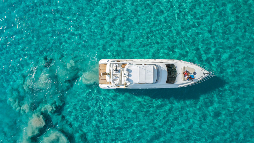 Un'immagine di un lussuoso yacht di lusso naviga in acque turchesi, con persone a bordo che godono del sole e del mare in Sardegna