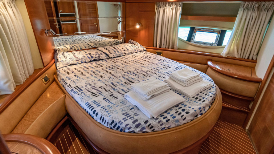 Letto matrimoniale con biancheria in una cabina di un yacht di lusso con finestra panoramica e specchio.