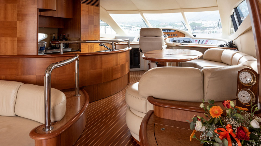 Interni lussuosi di un yacht con tavolo, poltrone e bar, vista panoramica sul mare dalla cabina di comando.