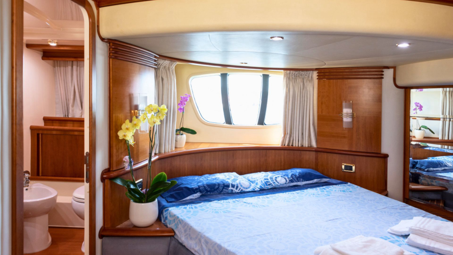 Una camera da letto con letto matrimoniale dello yacht, decorata con fiori e dotata di illuminazione interna.