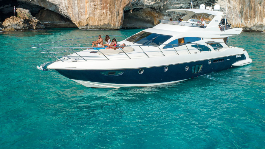 Yacht di lusso con passeggeri seduti sul ponte nelle acque cristalline della Sardegna