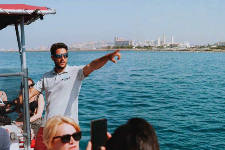 Lo skipper illustra la costa di Cagliari ai viaggiatori a bordo