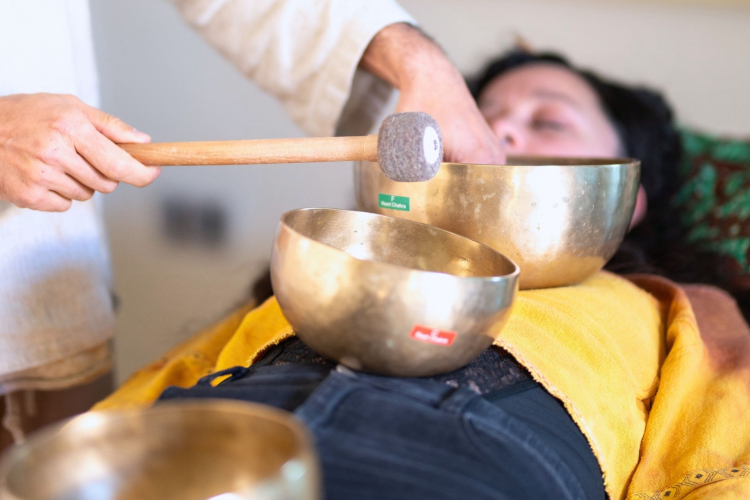 Trattamento di rigenerazione sonora applicato dalla guida su una donna con strumenti antichi a Cagliari