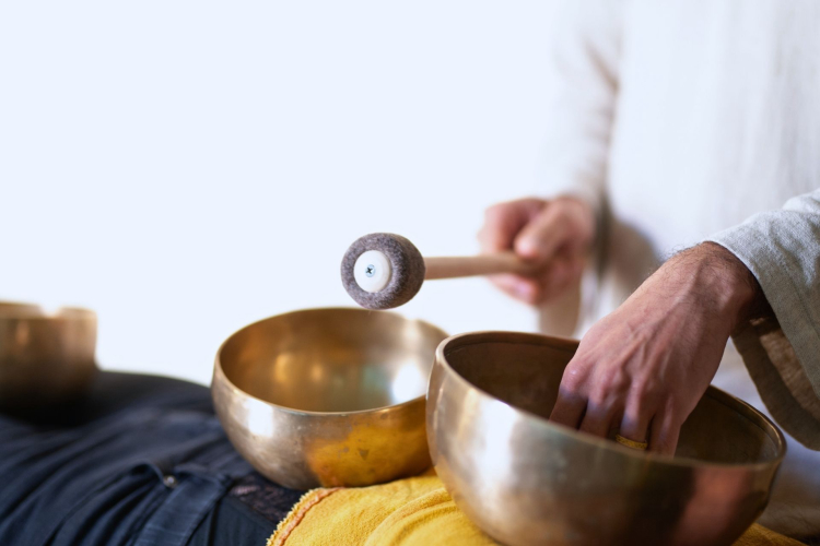 Una persona suona un gong e una campana di cristallo in un ambiente tranquillo, vicino al verde e a siti archeologici. L'esperienza si svolge in un contesto tranquillo, lontano dal caos cittadino, nel sud Sardegna.