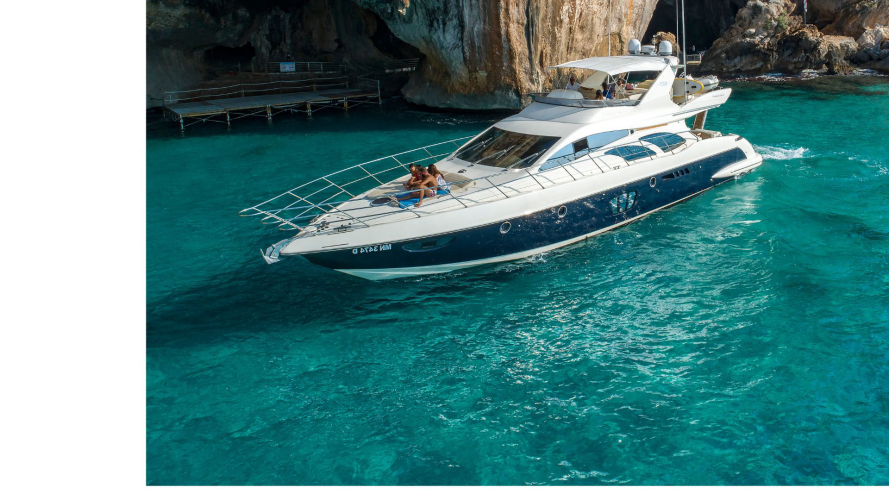 Yacht de luxe naviguant avec des personnes à bord, près d'une grotte dans le golfe d'Orosei