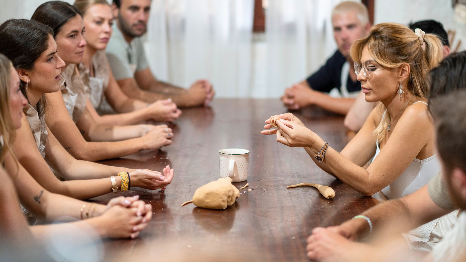Un groupe de personnes participe à un atelier de pain à Carasau en Sardaigne, en suivant des gestes anciens et en dégustant du vin et des produits locaux