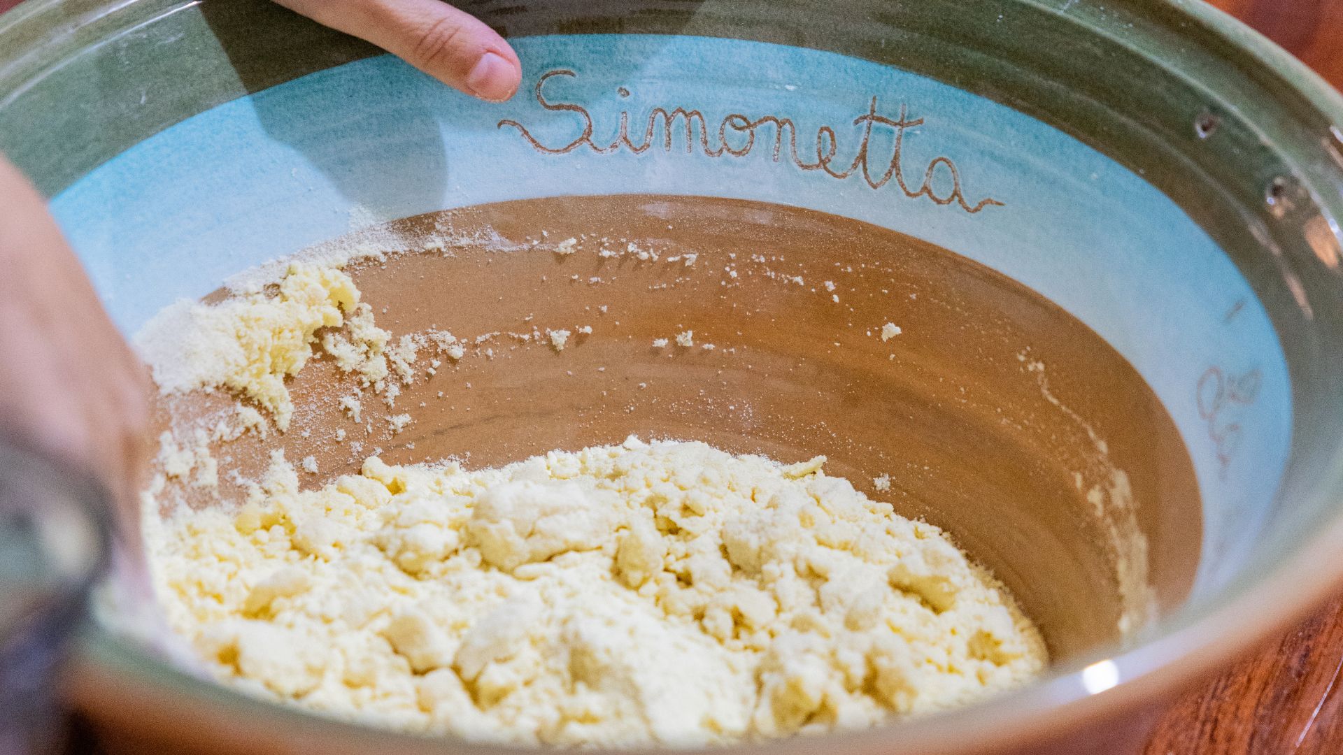 Une personne pétrit du pain Carasau dans un bol portant le nom de Simonetta, en suivant des gestes anciens