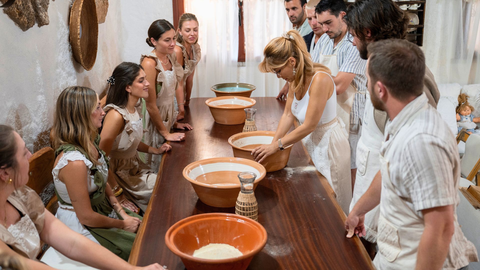 Groupe de personnes dans une ancienne cave, engagé dans la préparation du pain carasau