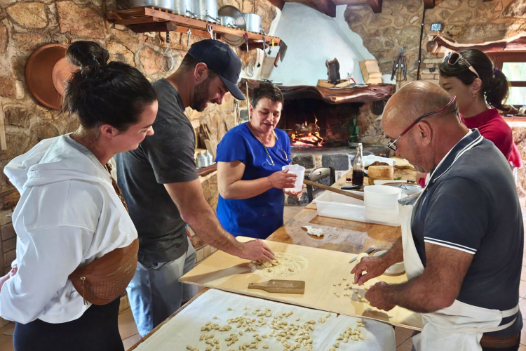 Un gruppo di persone partecipa ad un tour privato nella Blue Zone di Orosei, guidati da una guida locale attraverso paesaggi selvaggi sul mare. Visitano tombe nuragiche e boschi, e partecipano ad attività come la lavorazione del formaggio e un corso di cucina tradizionale.