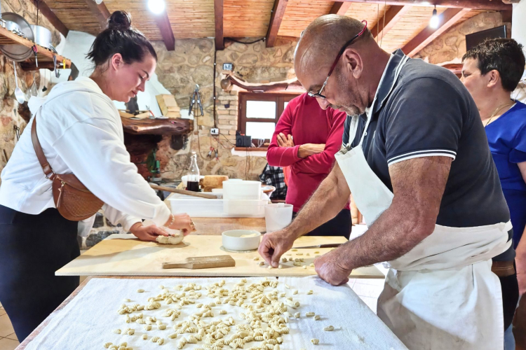 Gruppo di persone in una cucina che preparano pasta fresca, in un'azienda agricola rurale
